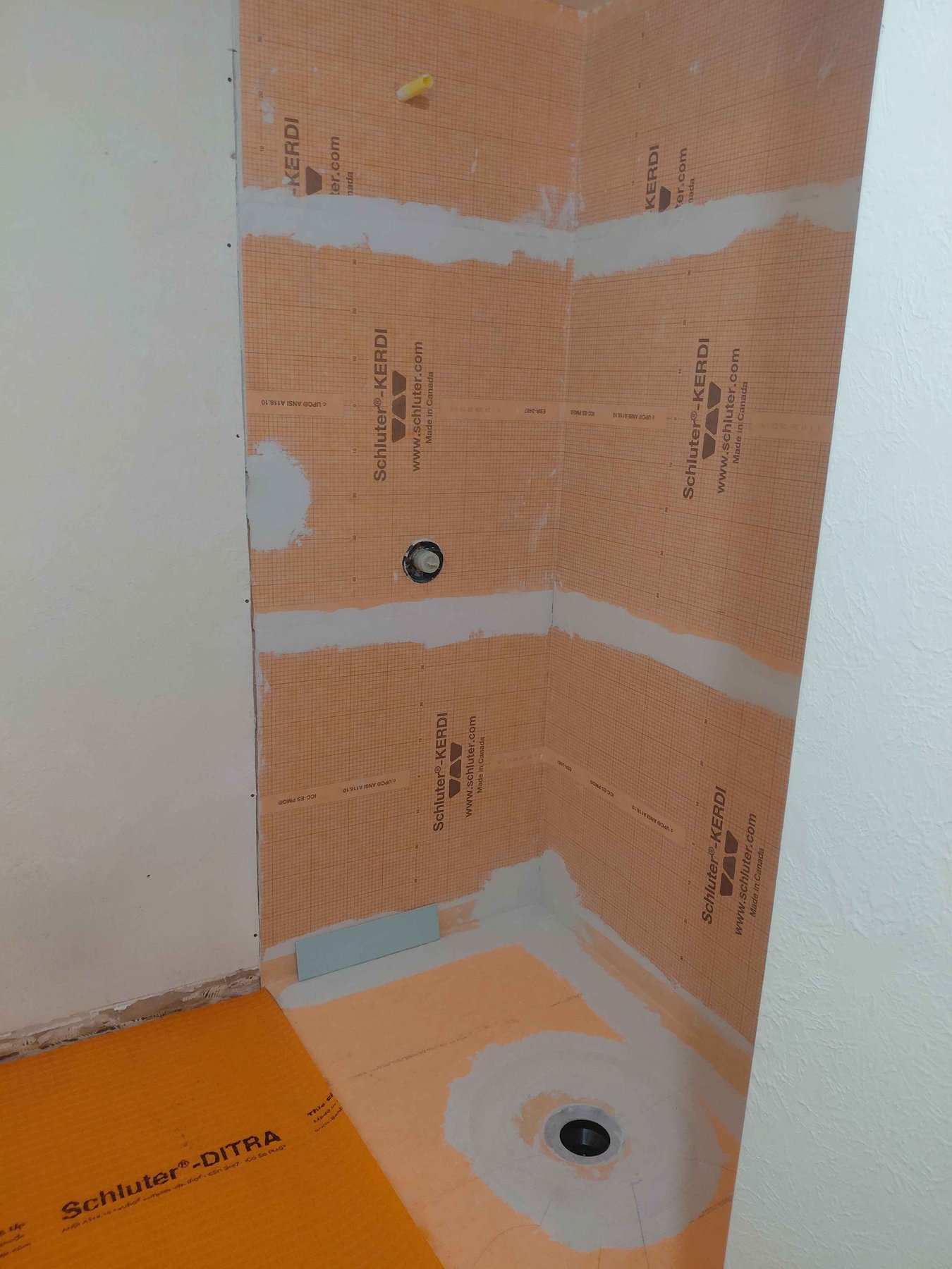 Shower stall waterproofed with Schluter-Kerdi membrane on the walls and Schluter-Ditra on the floor before tile install